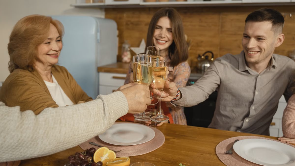 A happy group of people toasting with wine glasses at a cozy indoor dinner gathering.
